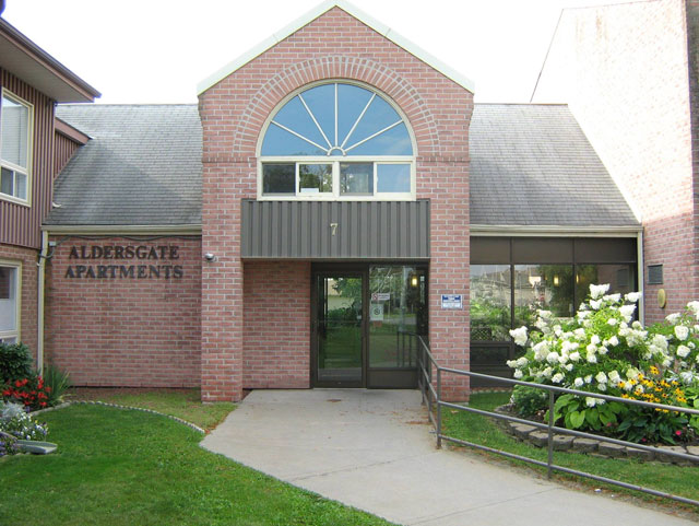 aldersgate office front entrance made of red brick with walking path and railing towards the door