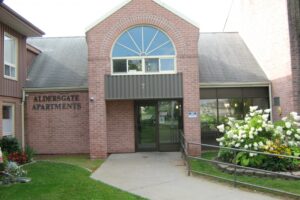 aldersgate office front entrance made of red brick with walking path and railing towards the door