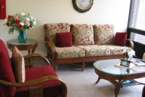 living room with matching wooden furniture including chair, couch set, glass top coffee and side table with bouquet of red and white flowers
