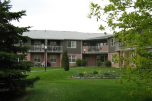 two story apartment buildings surrounded by lush grass and mature trees