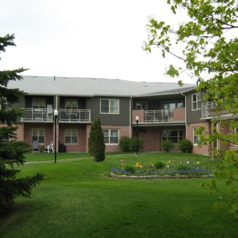 two story apartment buildings surrounded by lush grass and mature trees