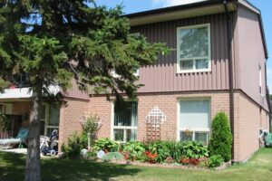 two story apartment unit with lush garden and mature pine tree