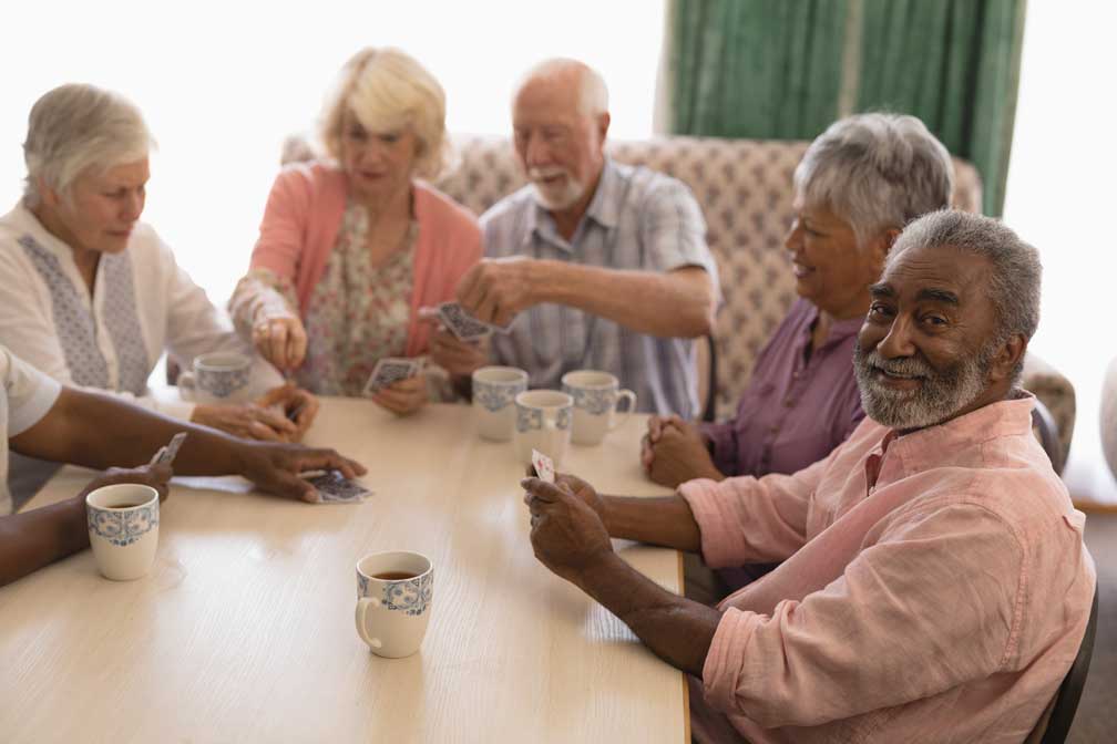 group of seniors having tea and playing cards